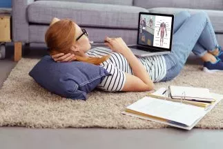 frau liegt mit laptop auf dem fußboden in ihrer wohnung